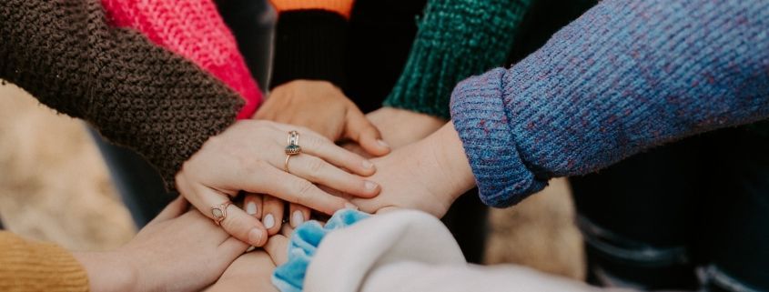 person in red sweater holding babys hand