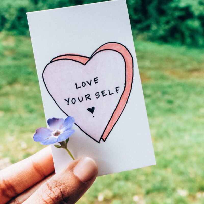 A hand holding a card saying "love yourself"
