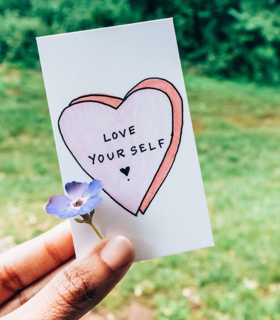 A hand holding a card saying "love yourself"